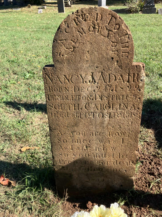 Close-up view of a weathered granite tombstone in Potosi Presbyterian Cemetery, featuring the inscription for Nancy J. Adair, born December 24, 1829, in Pendleton District, South Carolina, died February 13, 1839, in Potosi, Missouri, with a 19th-century memento mori verse: "As you are now, so once was I; as I am now, so you must be; prepare for death and follow me." The stone shows evidence of recent cleaning and resetting by the Steelville Trail of Tears Remembrance Committee.