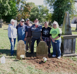 Committee members cleaning and resetting stones. Alt: “Members of the Steelville Trail of Tears Remembrance Committee cleaning and resetting two historic tombstones in Potosi Presbyterian Cemetery.
