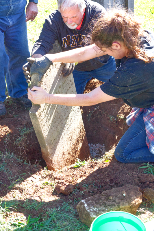 Committee members cleaning and resetting stones. Alt: “Members of the Steelville Trail of Tears Remembrance Committee cleaning and resetting two historic tombstones in Potosi Presbyterian Cemetery.